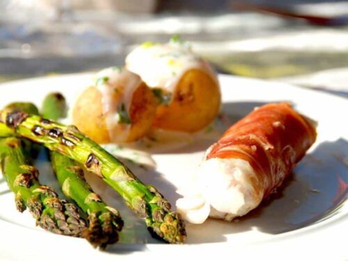 Grillede torskeruller er hurtig mad på grillen med benfri torskefilet, der omvikles med parmaskinke. Serveres med grillede grønne asparges, nye kartofler og en god persillesovs. Foto: Guffeliguf.dk.
