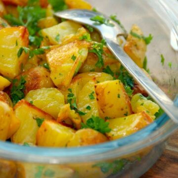 gode og nemme ovnstegte persillekartofler, der smager super godt til blandt andet frikadeller. Kartoflerne steges i ovnen, og vendes efterfølgende med persille. Foto: Guffeliguf.dk.