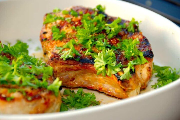 Møre og saftige Weber koteletter, der er grillede svinekoteletter med skaft eller ben. Koteletterne marineres i en hvidløgsolie, og grilles i gasgrill eller kuglegrill. Foto: Guffeliguf.dk.