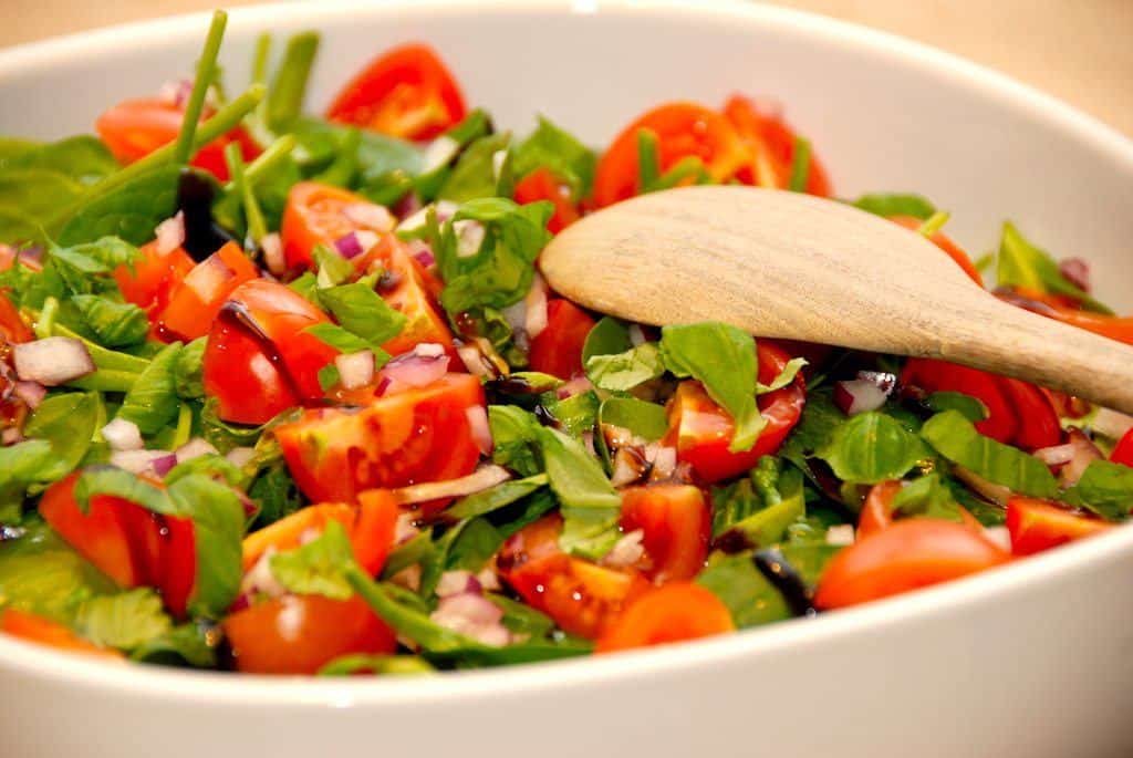 Flot og sund spinatsalat med cherrytomater og finthakket rødløg, der vendes med lidt balsamico og en god olivenolie. Foto: Guffeliguf.dk.