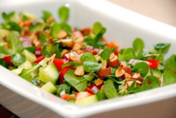 Salat med feldsalat og tomat. En dejlig salat, der også indeholder rødløg, peberfrugt og mandler. Hæld også lidt olivenolie og citronsaft over. Foto: Guffeliguf.dk.