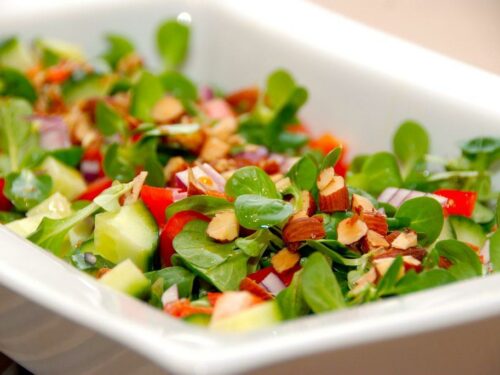 Salat med feldsalat og tomat. En dejlig salat, der også indeholder rødløg, peberfrugt og mandler. Hæld også lidt olivenolie og citronsaft over. Foto: Guffeliguf.dk.