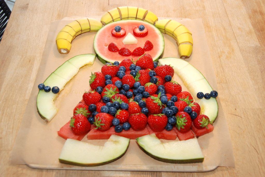 Sådan skal den færdige kagemand af frugt se ud. Med hoved og krop af vandmelon, hår af tre bananer, kjole af jordbær og blåbær, mens arme og ben er lavet af frøskindsmelon. Foto: Madensverden.dk.