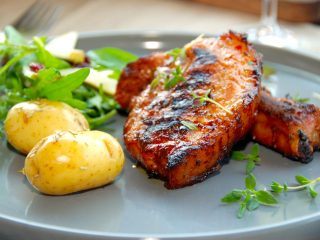 Grillede revelsben med nye kartofler i grillen er rigtig sommermad, der har masser af smag. Kartoflerne forkoges, inden de vendes med rosmarin og steges færdige i grillen. Foto: Madensverden.dk.