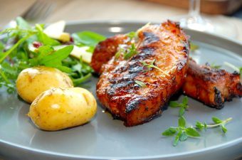 Grillede revelsben med nye kartofler i grillen er rigtig sommermad, der har masser af smag. Kartoflerne forkoges, inden de vendes med rosmarin og steges færdige i grillen. Foto: Madensverden.dk.