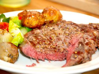 En velstegt ribeye med bagte løg og hjertesalat er rigtig hyggemad, der samtidig kan tilberedes hurtigt. Foto: Madensverden.dk.