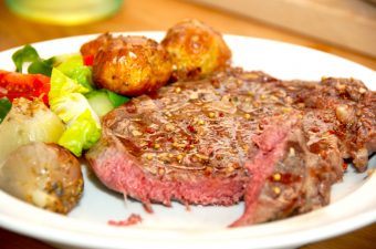 En velstegt ribeye med bagte løg og hjertesalat er rigtig hyggemad, der samtidig kan tilberedes hurtigt. Foto: Madensverden.dk.