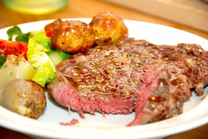 En velstegt ribeye med bagte løg og hjertesalat er rigtig hyggemad, der samtidig kan tilberedes hurtigt. Foto: Madensverden.dk.