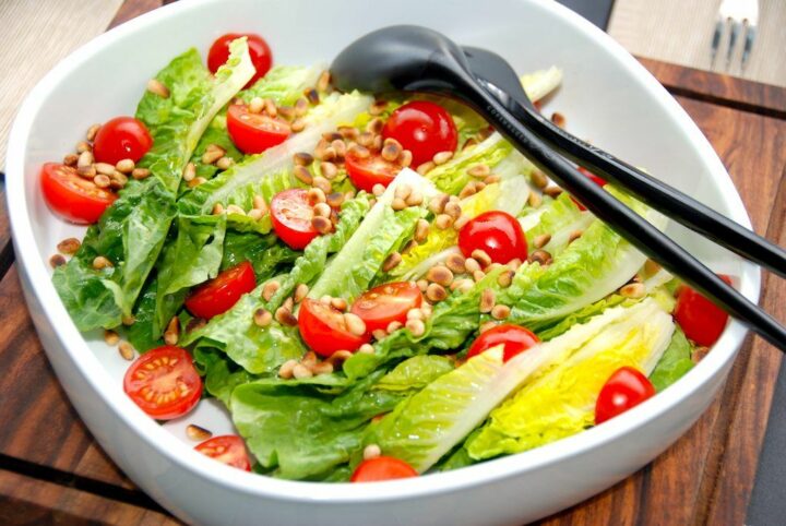 En virkelig lækker og særdeles nem romainesalat med tomater og pinjekerner. Den sprøde salat dryppes med lidt citronsaft og olivenolie. Foto: Madensverden.dk.