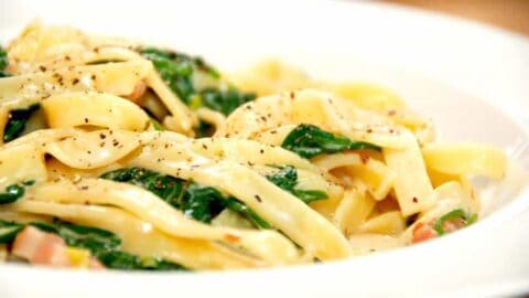 Pasta med spinat og hvidløg er nem og hurtig hverdagsmad med masser smag. Pastaretten laves også med bacon og forårsløg, og det hele samles i en nem og cremet flødesovs. Foto: Madensverden.dk.
