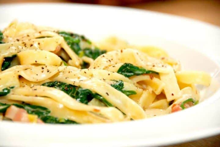 Pasta med spinat og hvidløg er nem og hurtig hverdagsmad med masser smag. Pastaretten laves også med bacon og forårsløg, og det hele samles i en nem og cremet flødesovs. Foto: Madensverden.dk.