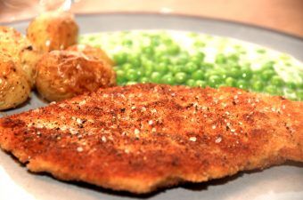 Paneret kylling smager fantastisk godt, og kan sagtens måle sig med en klassisk wienersschnitzel. Her er den serveret me stuvede ærter og ovnbagte kartofler. Foto: Madensverden.dk.