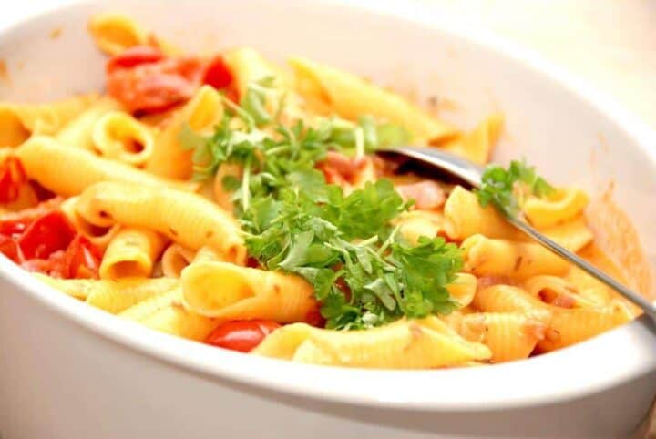 En super lækker og nem pasta opskrift med bacon og cherrytomater på dåse, der koges med lidt fløde. Pasta vendes i og der pyntes med lidt persille. Foto: Madensverden.dk.