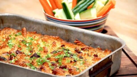 Et lækkert pastafad med bacon, der er serveret med gnavegrønt i form af gulerødder og agurk og stave. Pastafadet bages cirka 50 minutter i ovnen. Foto: Madensverden.dk.