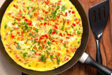 En lækker og åben omelet, der laves med blandt andet rød peberfrugt og bacon. Omeletten er ret hurtig at lave, og den er god til både morgenmad og frokost. Foto: Madensverden.dk.