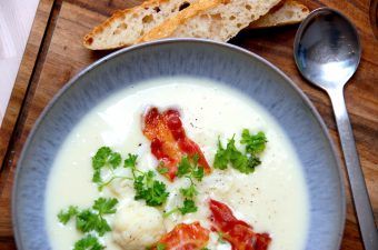 Det er nemt at lave en cremet blomkålssuppe, som her på billedet er anrettet med sprøde stykker bacon, dampet blomkål og lidt persille. Blomkålssuppen laves med blomkål og lidt kartoffel, der koges i bouillon. Suppen kan både bruges som forret og hovedret. Foto: Madensverden.dk.