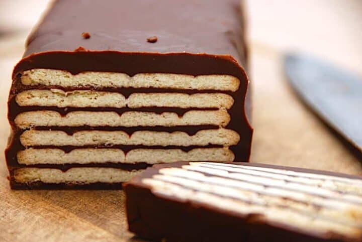 A chocolate cake with a knife on a cutting board.