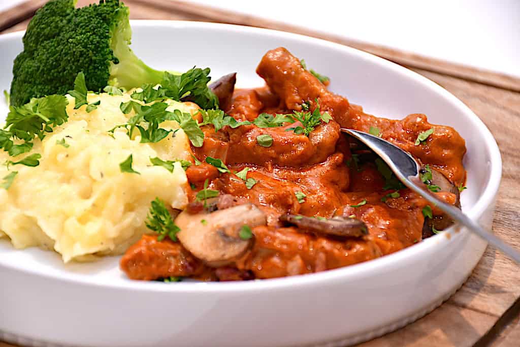 servering af bøf stroganoff med kartoffelmos og dampet broccoli
