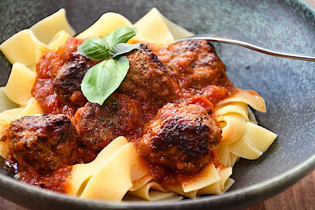 Billede med italienske kødboller i tomatsaovs serveret med pasta.