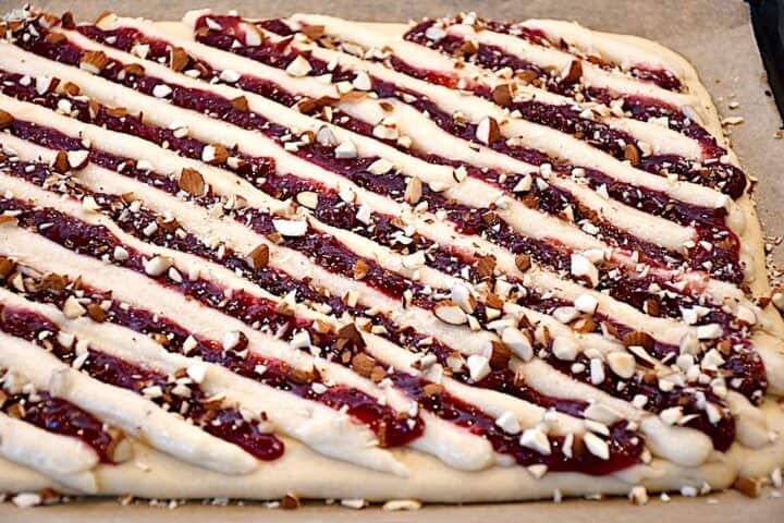 top mørdejsbunden med makronmasse, hindbærmarmelade og hakkede mandler