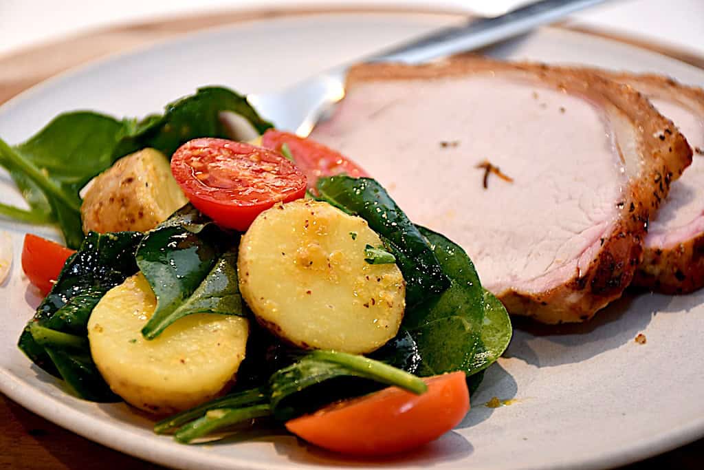 frisk kartoffelsalat med spinat serveret med flæskesteg