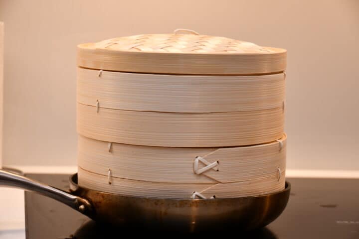 damp dine bao-boller i en bambus damper i pande eller gryde