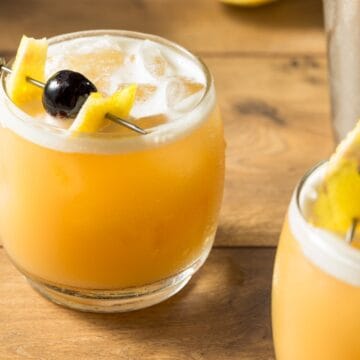 Amaretto Sour cocktail med mandellikør, citron og bourbon, serveret med isterninger og skum på toppen.